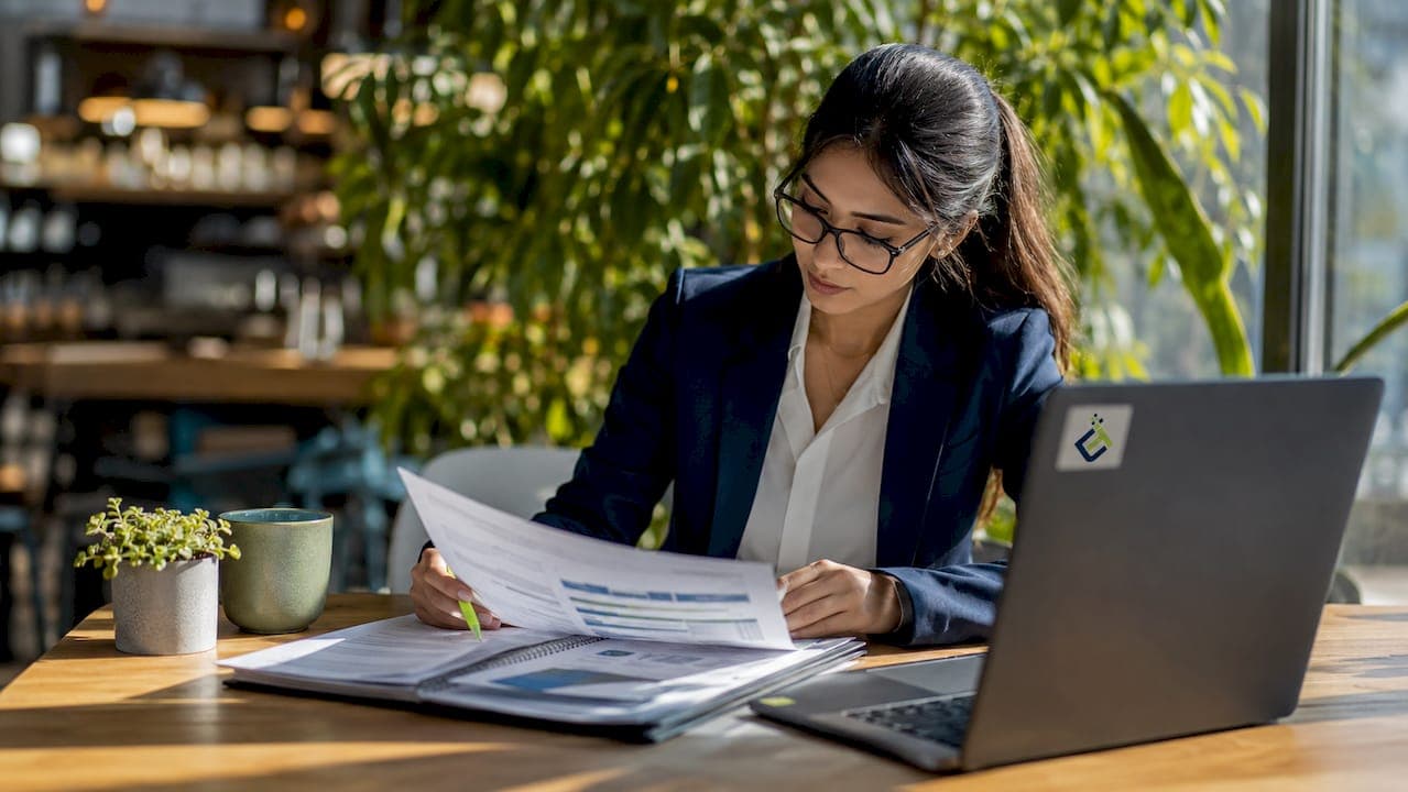 Female payroll analyst reviewing reports at desk